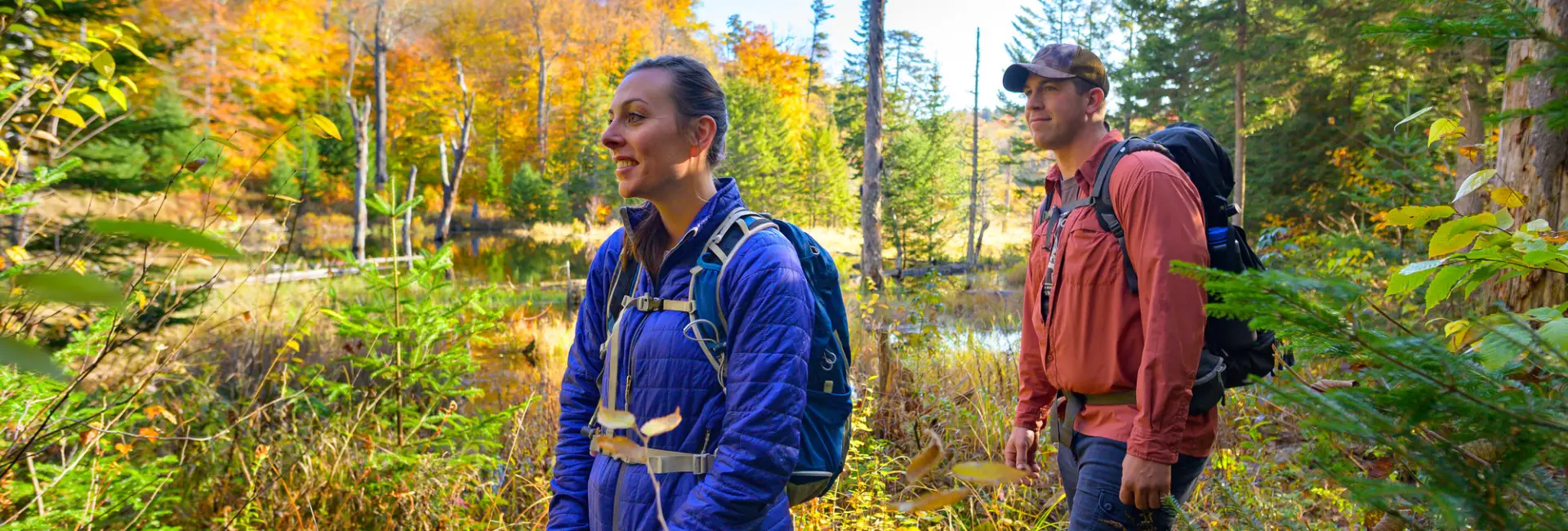 A man and woman walk a fall trail. 