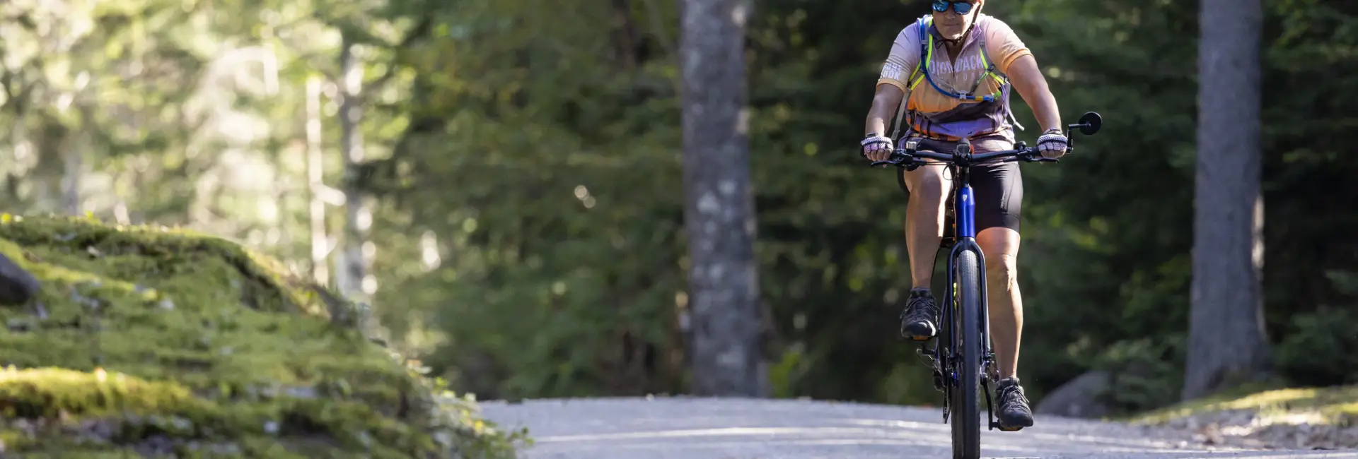 A man bikes on a calm trail in the woods. 