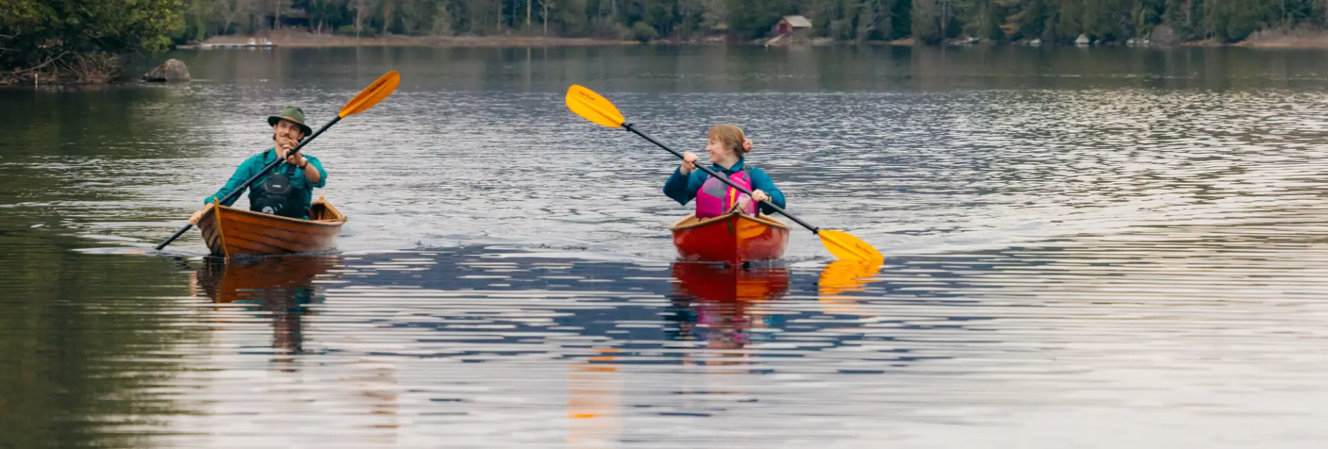 Two people paddle on a lake in spring. 