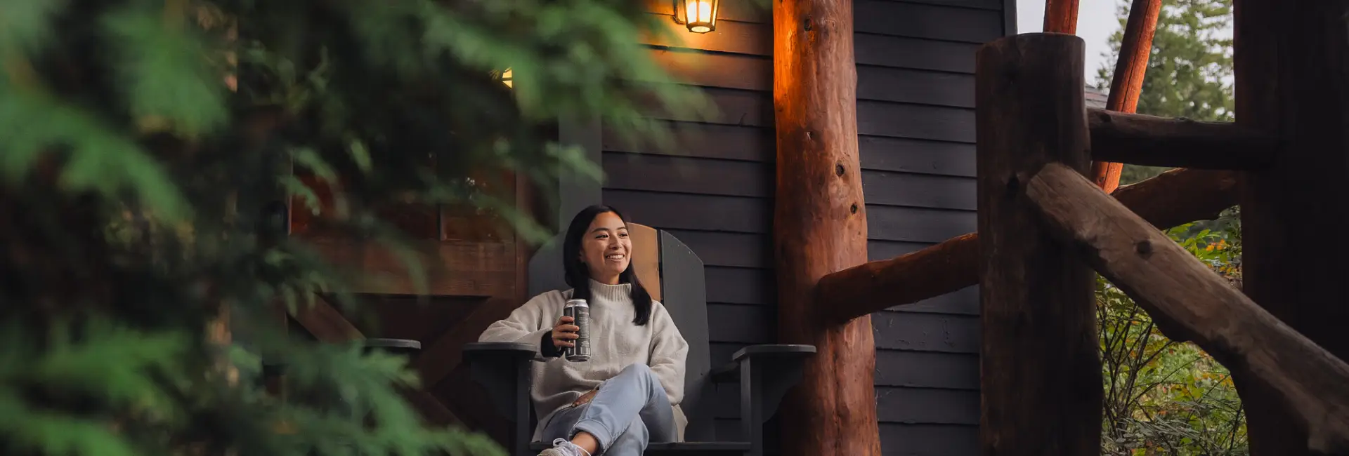 A woman sits on a porch of a cottage in fall.