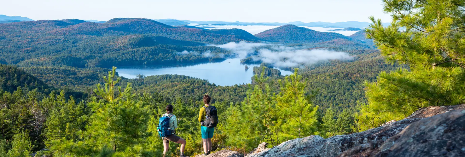 Two people stand on top of a mountain. 