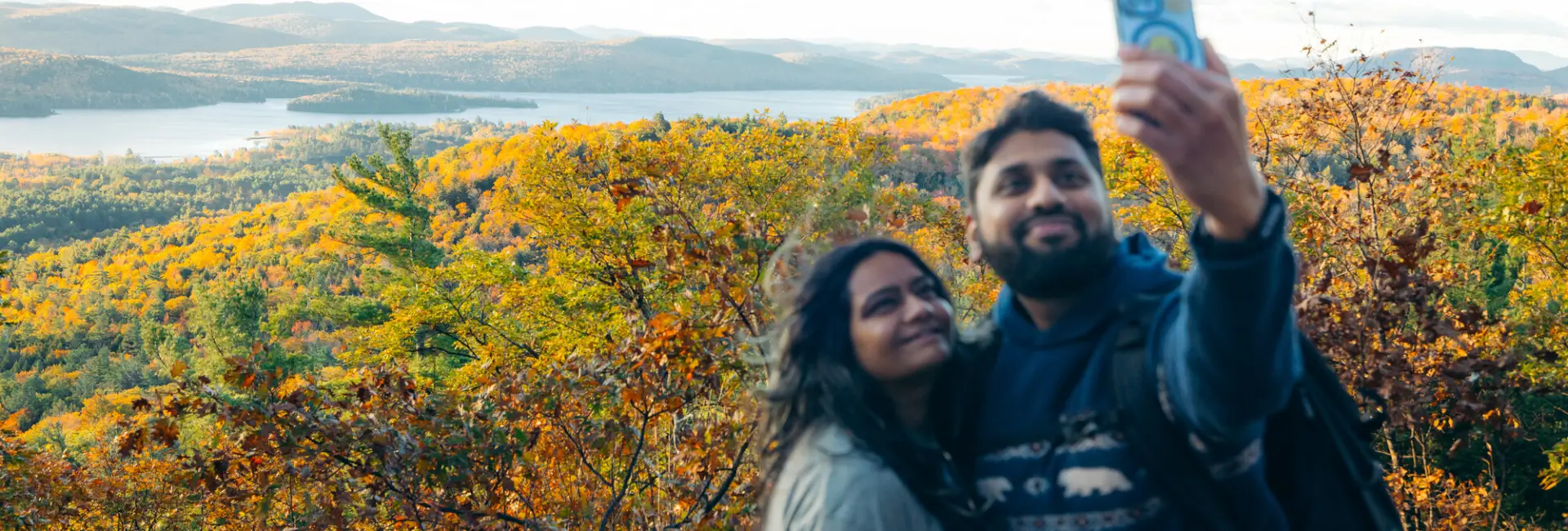 A man and woman take a selfie on top of a fall mountain. 