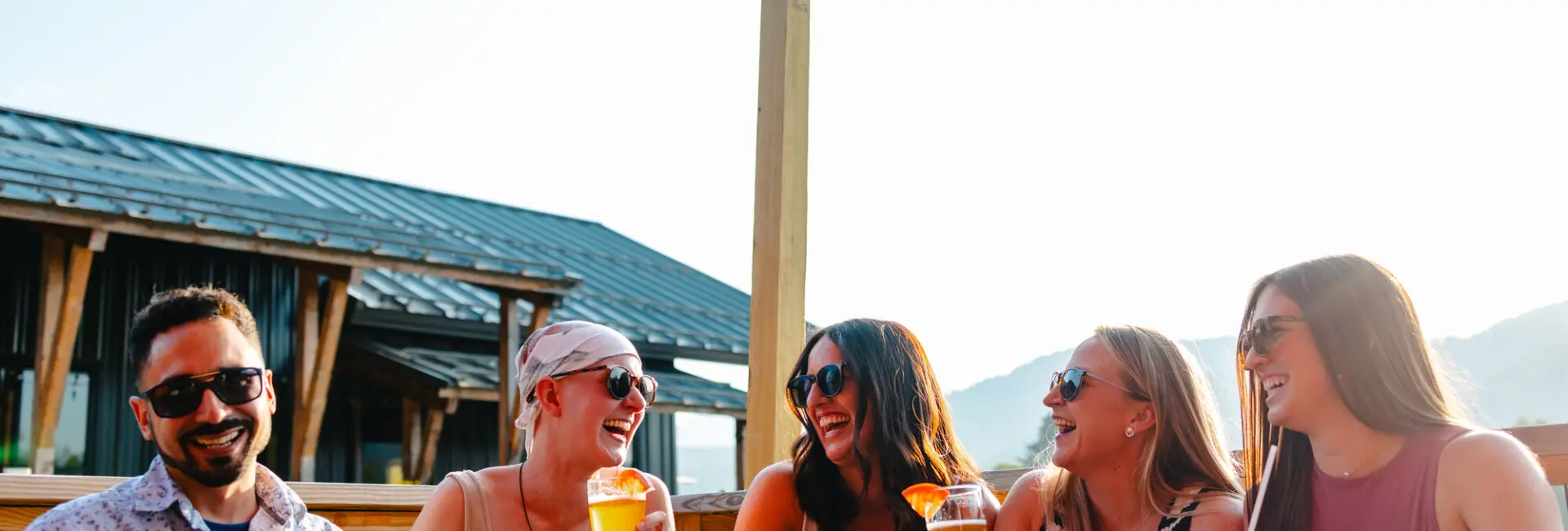 A group of friends share beers at an outdoor restaurant. 