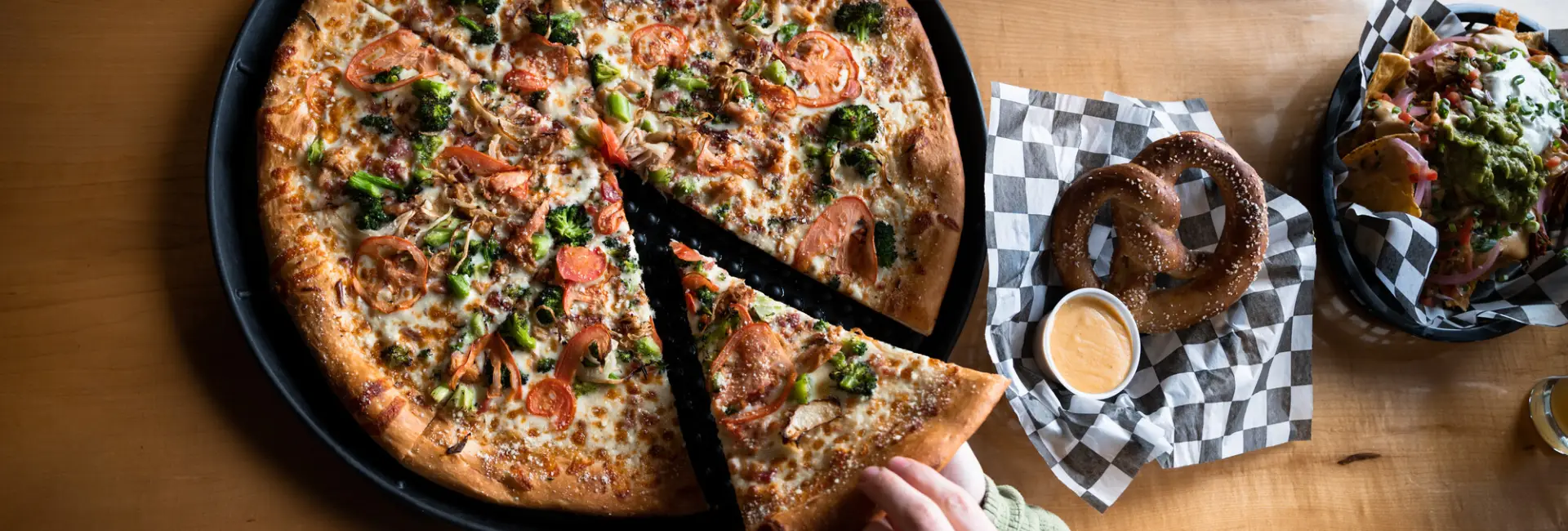 A person digs into pizza and a pretzel. 