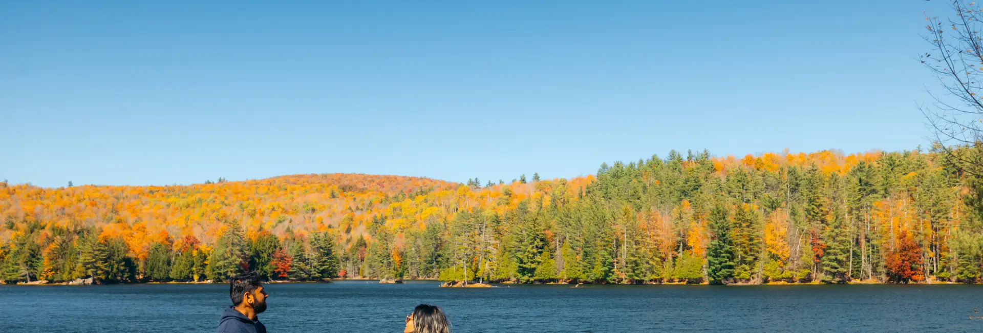 A man and woman sit on a fall beach. 