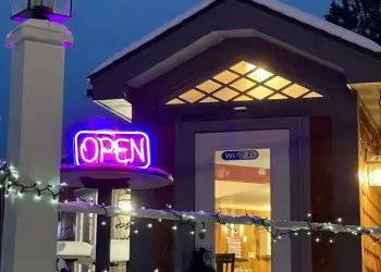 Waypoint Cafe front entrance at night , A fancy latte at Waypoint Cafe, Soup at Waypoint Cafe in Long Lake, Open faced sandwich at Waypoint Cafe, A hot cup of coffee on a table in a to-go cup with custom Waypoint Cafe sticker leaning against it., The inviting front counter is stuffed with delicious options and warm lighting, Signs leading the way to Espresso at the Waypoint Cafe next to a dock and the lake, The view of the lake out the window of the cozy dining space in the Waypoint Cafe