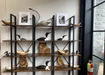 A wooden and metal shelf displaying carvings, Colorful art on the walls, Shelves of carvings