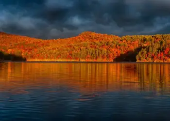The trees are gorgeous in the fall., Many interesting shoreline rocks were shaped by water., This is a day for paddling., Eagle Lake is a good place for loon spotting., Eagle Lake has views of the mountains., Line up for a wonderful Adirondack sunset photo.
