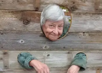 An older woman in the wooden stocks.