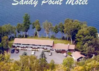 An aerial view of Sandy Point Motel, A sandy beach with docks., The parking area looking at the rooms and balcony at Sandy Point Motel., A two bed room looking out large windows on a balcony., Raging waters