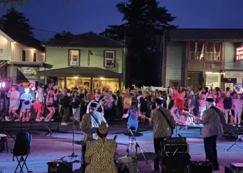 A band plays and people dance in the street in the evening.