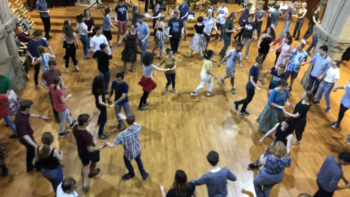 a gymnasium of people contra dancing