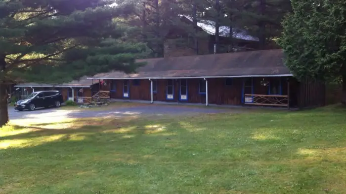 The large lawn and exterior of the brown building and white trim of the Blueberry Hill Motel