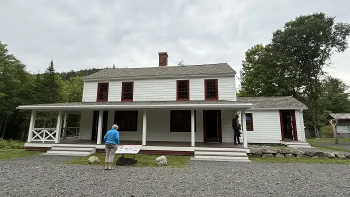 A visitor stands in front of a historic white home