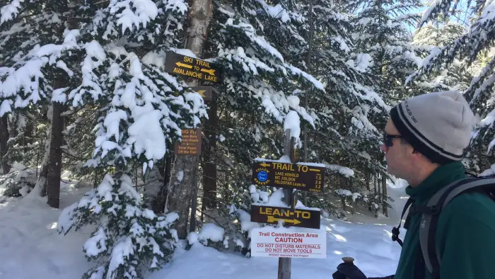 A hiker checking out trail signs at a junction in the winter