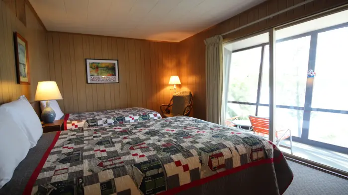 A two bed room looking out large windows on a balcony.