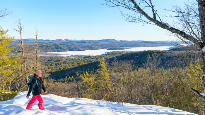 Winter view from mountain summit overlooking lake with girl hiking