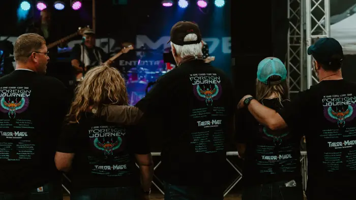 Concert-goers in band t-shirts watch show