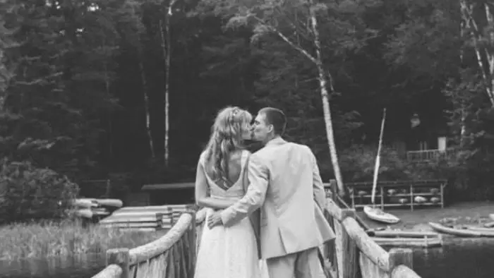 A bride and groom on the bridge share a kiss.