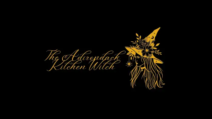 Image of a woman's profile wearing a pointed witch hat covered in flowers and a spider on a thread hanging down the front.