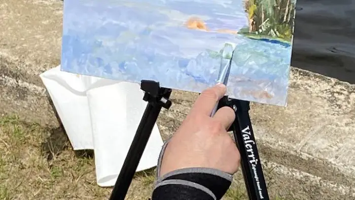 Three people standing at their easles painting the natural scene before them