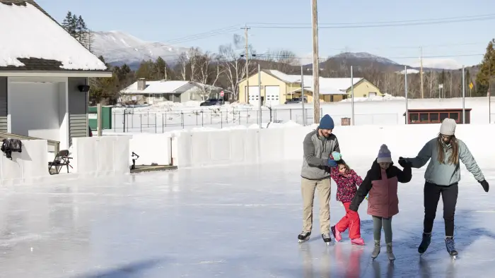 A family ice skates at an outdoor rink