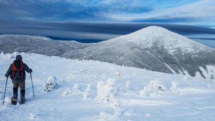 A snowshoer on a high alpine peak in the winter