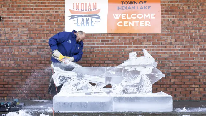 Man carving a snowmobile out of ice