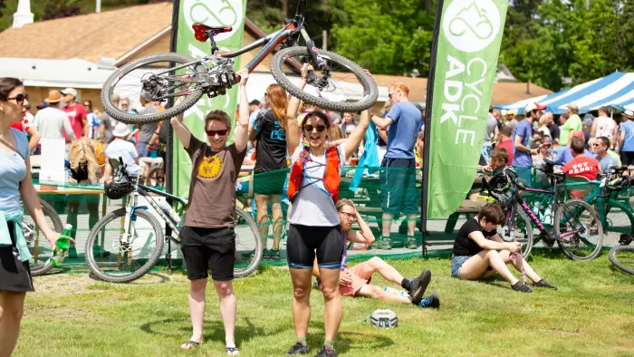 A woman in cycling gear rides a bike on a dirt trail in a forest during the Black Fly Challenge.