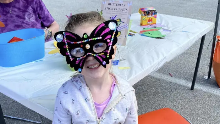 a little girl wearing a butterfly mask that she decorated