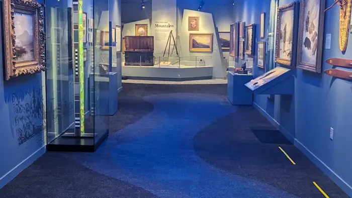 Art pieces on display in a long hallway with blue walls