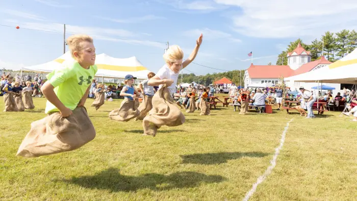 Kids cross finish line in sack races.