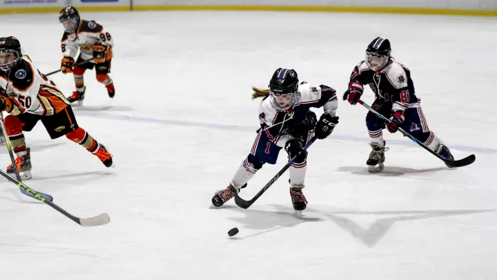 A synchronized ice skating team performs a routine in matching pink and black outfits