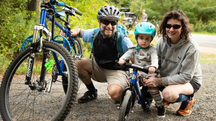 Smiling young family with toddler kick bike