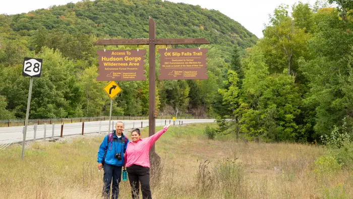 Two hikers in front of the sign for OK Slip Falls