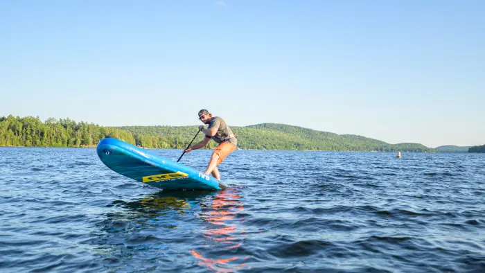 A paddleboarder getting some air on a lake