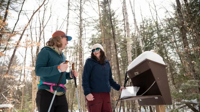 Two crosscountry skiers signing in at the Big Pond trailhead register