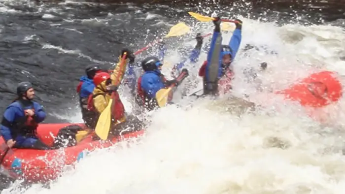 Paddles up overhead while hitting the white water
