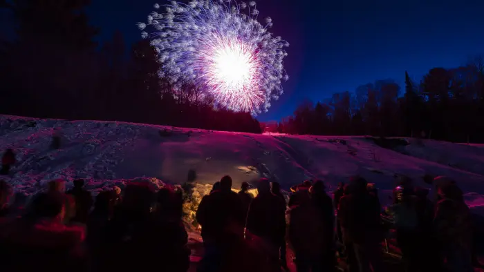 fireworks above a group of people around a bon fire