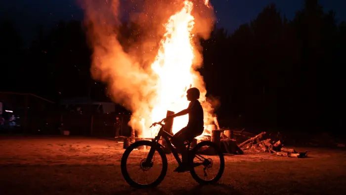 Bicyclist rides past a big bonfire