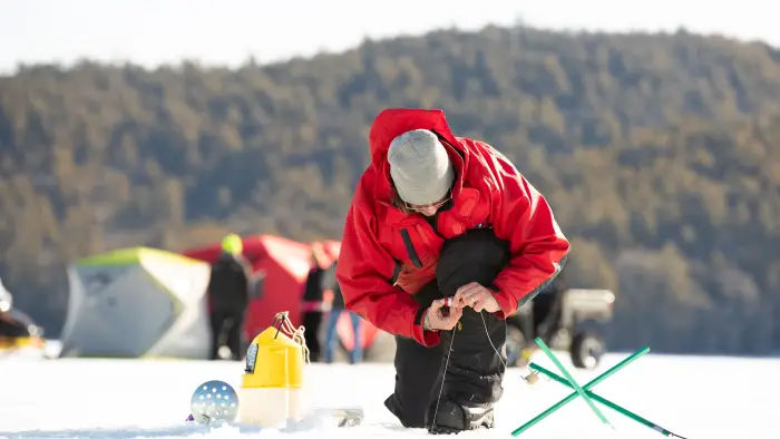Man setting up his tip up for an ice fishing derby on a frozen lake.