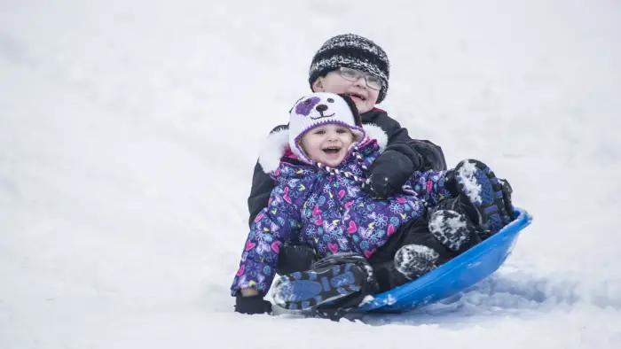 two kids sledding on one sled together