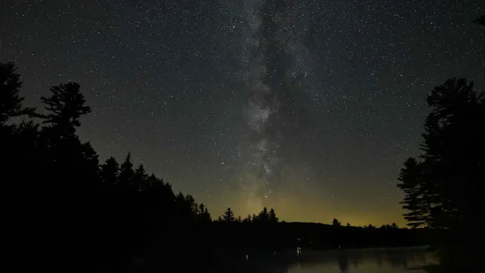 The glorious milky way seen through dark skies over the lake and surrounding pines