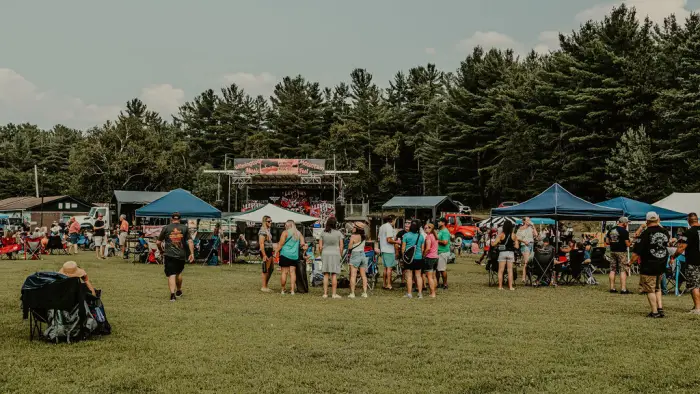 Music festival crowd seen in field with pop-up tents
