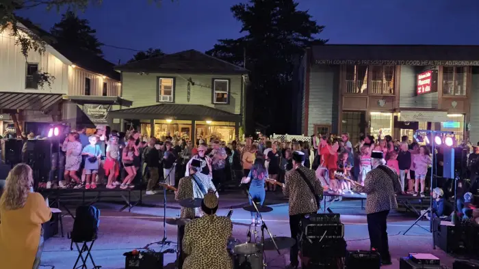 A band plays and people dance in the street in the evening.