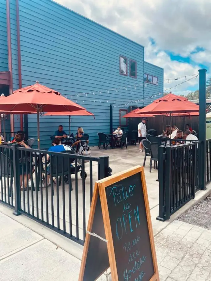 An outdoor dining area with small tables and red umbrellas.