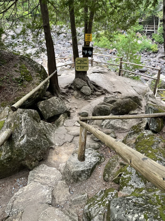 a fenced outlook looks over a stream filled with pebbles and rocks.