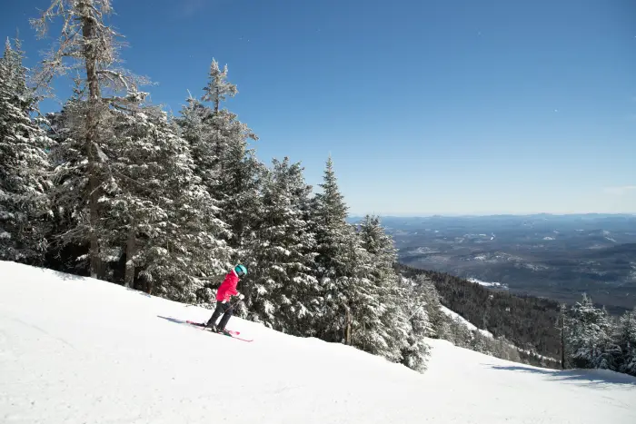 A skier speeds down a mountain on a sunny day in winter.