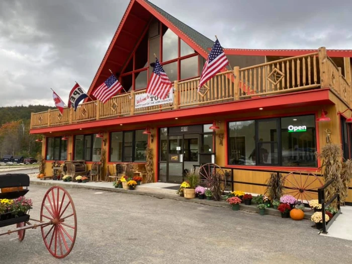 A red and brown building with fall flowers and flags on the exterior.