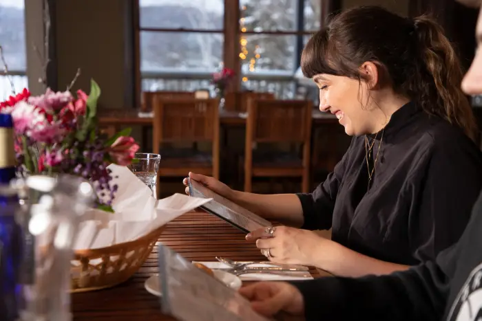 A woman sits at a restaurant table reading a menu